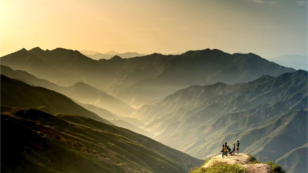 An image of a mountainous landscape set against a rising sun