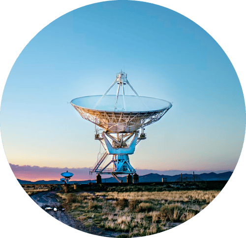Image of a satellite dish in a field, pointing into a clear blue sky