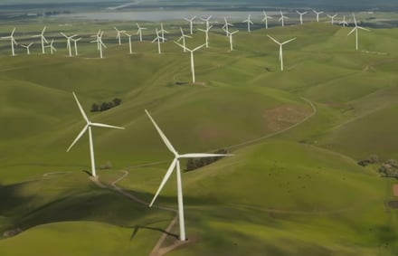 Image of wind turbines atop green hills